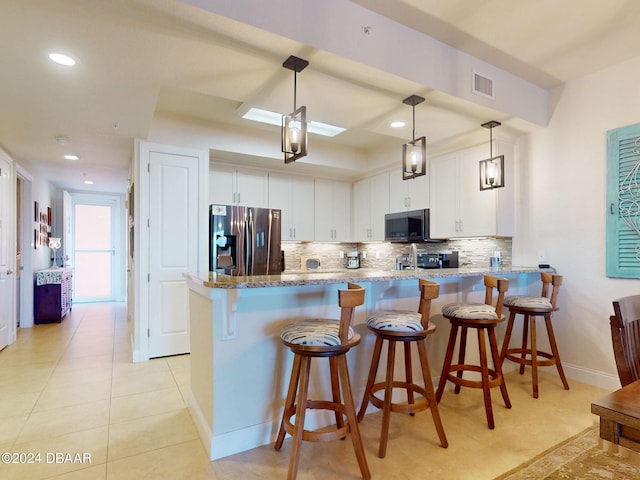 kitchen featuring light stone counters, pendant lighting, kitchen peninsula, white cabinetry, and appliances with stainless steel finishes