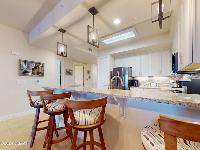 kitchen with white cabinets, a breakfast bar, hanging light fixtures, and stainless steel fridge with ice dispenser