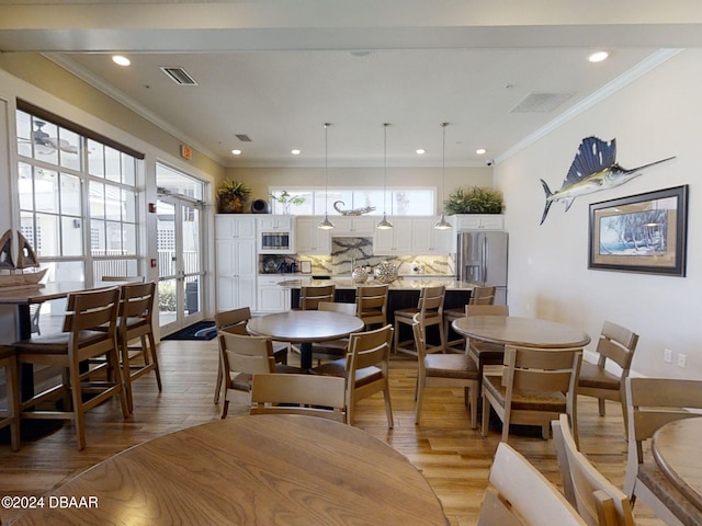 dining space featuring light hardwood / wood-style floors and crown molding