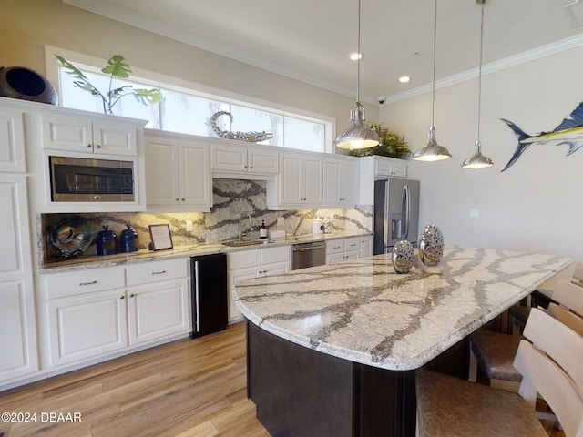 kitchen featuring white cabinets, appliances with stainless steel finishes, hanging light fixtures, and a kitchen island