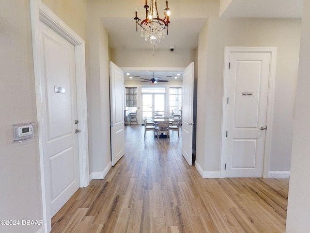 hall featuring light wood-type flooring and a notable chandelier