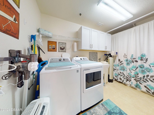 washroom with cabinets, washer and dryer, and a textured ceiling