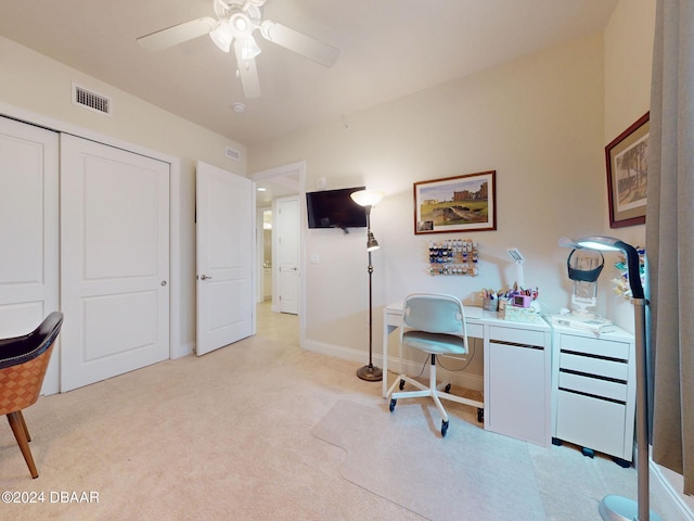 home office featuring built in desk, ceiling fan, and light carpet