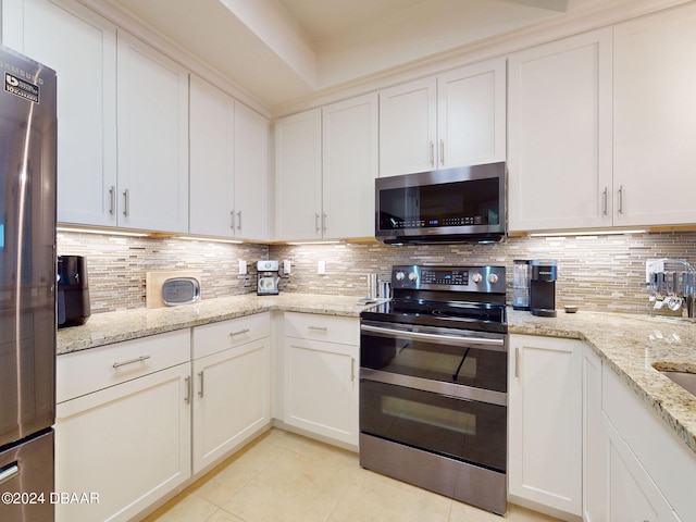 kitchen with light stone countertops, white cabinetry, decorative backsplash, and appliances with stainless steel finishes