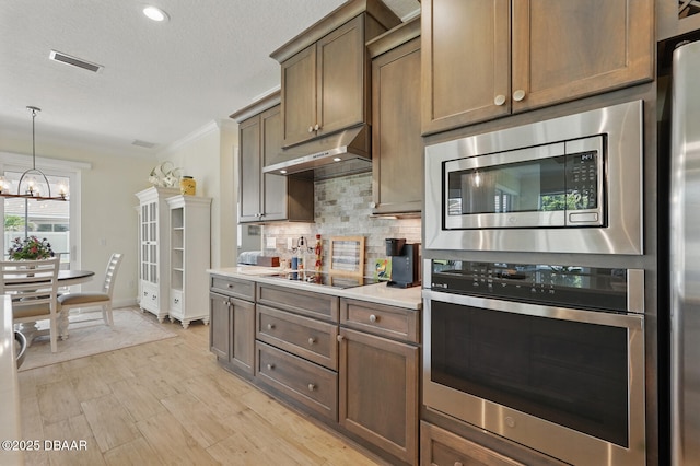 126 Briargate Look, Ormond Beach, FL 32174 - kitchen with appliances with stainless steel finishes, under cabinet range hood, tasteful backsplash, crown molding, and a chandelier