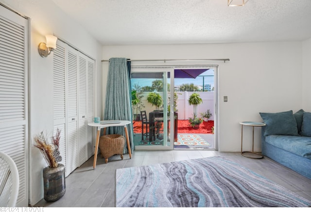 bedroom with access to exterior, light tile patterned floors, a textured ceiling, and a closet