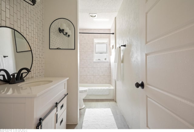 full bathroom featuring tiled shower / bath, a textured ceiling, vanity, tile patterned floors, and toilet