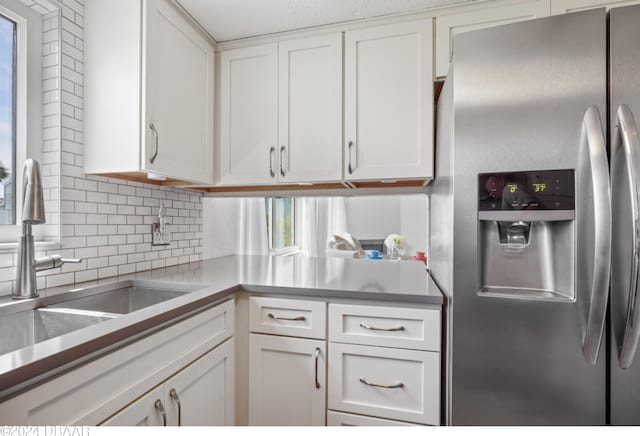 kitchen with stainless steel fridge with ice dispenser, a healthy amount of sunlight, and white cabinets