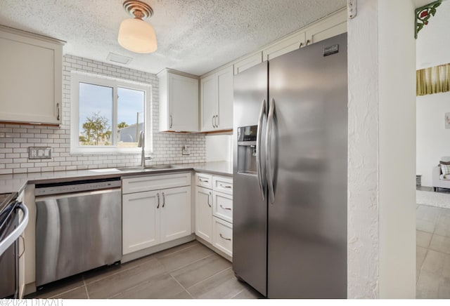 kitchen with stainless steel appliances, white cabinets, sink, tasteful backsplash, and light tile patterned floors