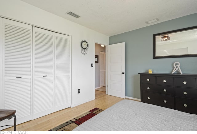 bedroom featuring wood-type flooring, a textured ceiling, and a closet