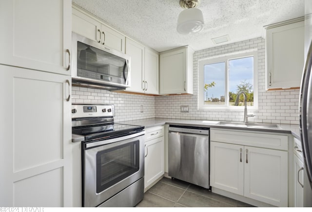 kitchen with sink, appliances with stainless steel finishes, a textured ceiling, backsplash, and tile patterned floors