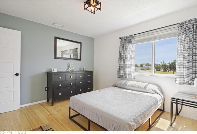 bedroom featuring a textured ceiling and light hardwood / wood-style flooring