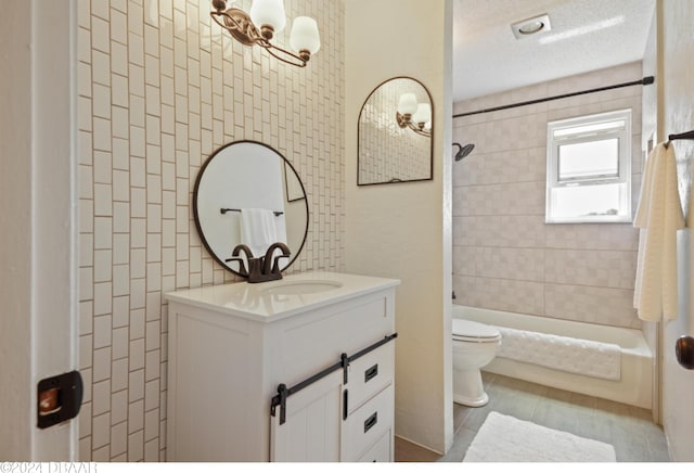 full bathroom featuring toilet, tile patterned flooring, tiled shower / bath, a textured ceiling, and vanity