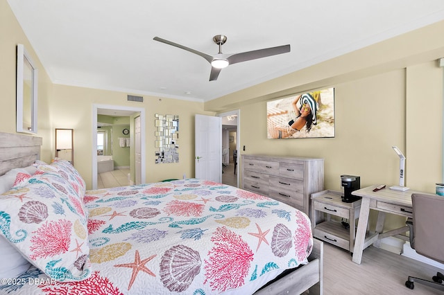 bedroom featuring wood finished floors, a ceiling fan, visible vents, ensuite bath, and ornamental molding