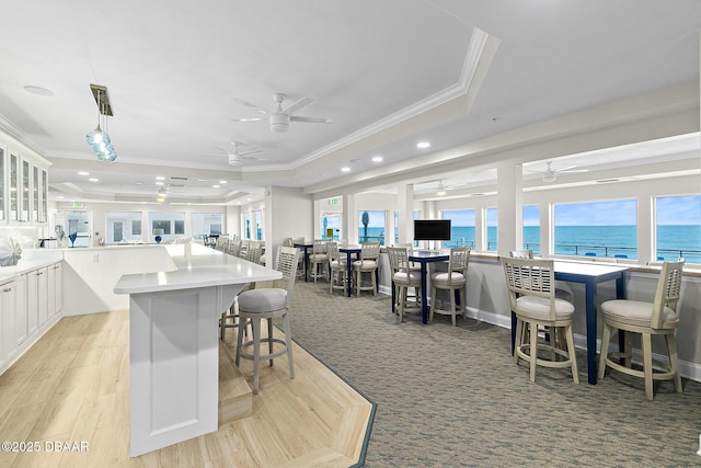 kitchen featuring a tray ceiling, ceiling fan, and ornamental molding