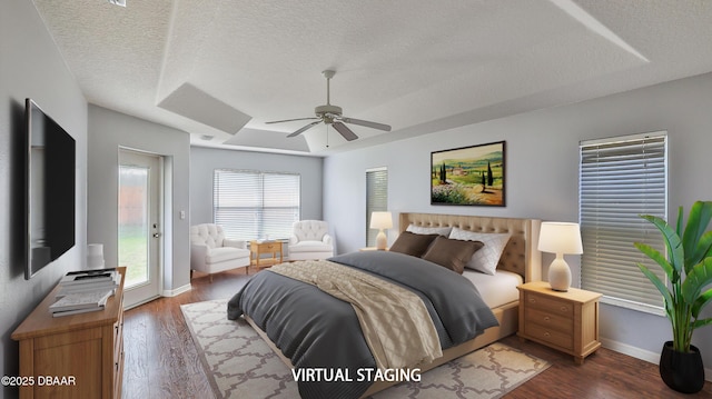 bedroom featuring ceiling fan, dark hardwood / wood-style floors, a tray ceiling, a textured ceiling, and access to outside