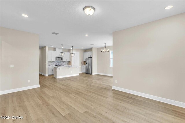 3116 Legends Preserve Dr, Daytona Beach, FL 32124 - unfurnished living room with a chandelier, light wood-style floors, baseboards, and recessed lighting