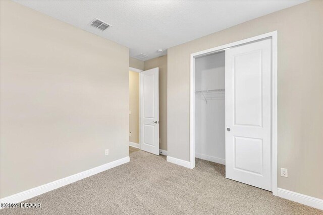 3116 Legends Preserve Dr, Daytona Beach, FL 32124 - unfurnished bedroom featuring light colored carpet, baseboards, a closet, and a textured ceiling
