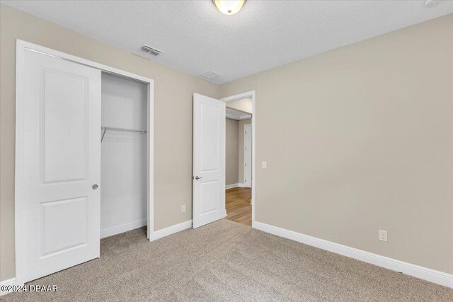 3116 Legends Preserve Dr, Daytona Beach, FL 32124 - unfurnished bedroom with carpet flooring, baseboards, a closet, and a textured ceiling