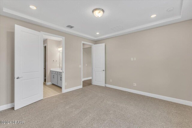 3116 Legends Preserve Dr, Daytona Beach, FL 32124 - unfurnished bedroom with light colored carpet, baseboards, recessed lighting, connected bathroom, and a raised ceiling