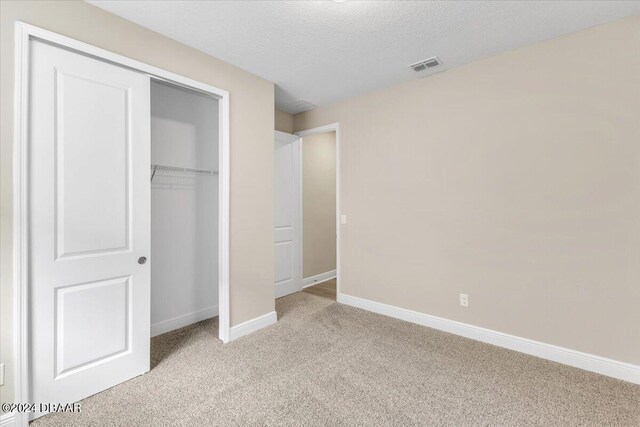 3116 Legends Preserve Dr, Daytona Beach, FL 32124 - unfurnished bedroom with light colored carpet, baseboards, a closet, and a textured ceiling