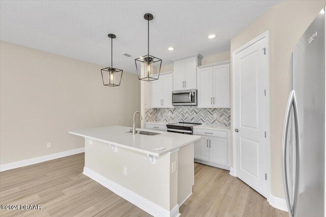 3116 Legends Preserve Dr, Daytona Beach, FL 32124 - kitchen featuring appliances with stainless steel finishes, a sink, backsplash, light wood finished floors, and a center island with sink