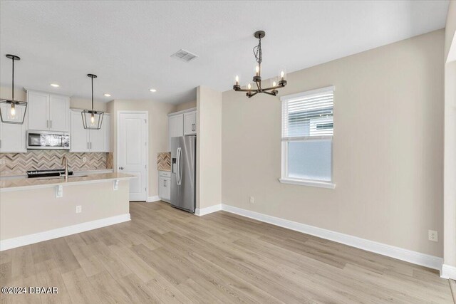 3116 Legends Preserve Dr, Daytona Beach, FL 32124 - kitchen with stainless steel appliances, a chandelier, decorative backsplash, a sink, and light countertops