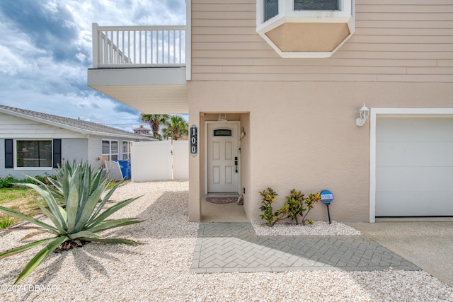 view of exterior entry featuring a balcony and a garage