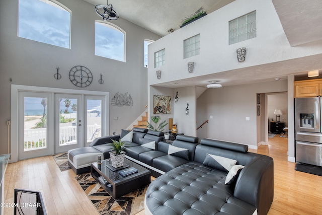 living room with a towering ceiling and light wood-type flooring