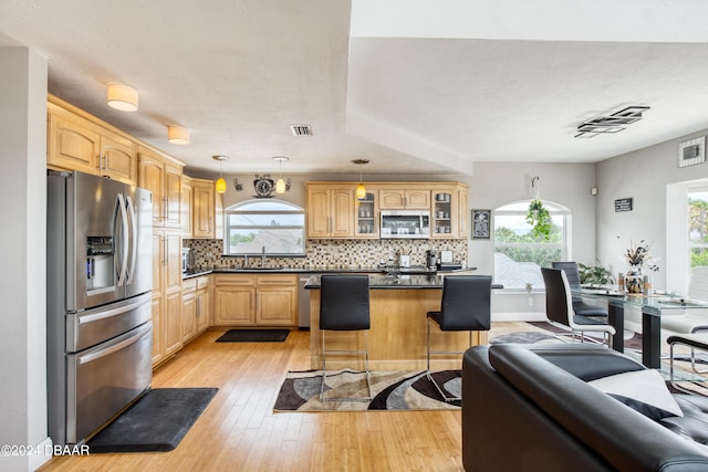 kitchen featuring stainless steel appliances, plenty of natural light, pendant lighting, a breakfast bar, and a kitchen island