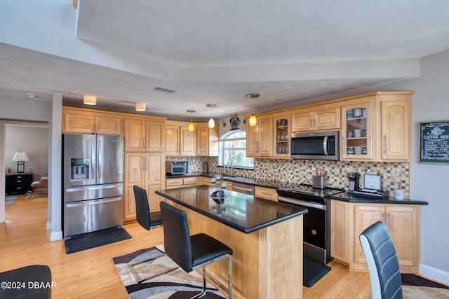 kitchen featuring sink, decorative light fixtures, a kitchen bar, a kitchen island, and appliances with stainless steel finishes