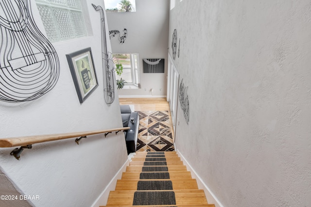 staircase featuring wood-type flooring and a high ceiling