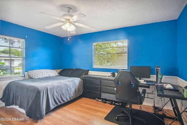 bedroom featuring a textured ceiling, ceiling fan, and light hardwood / wood-style flooring