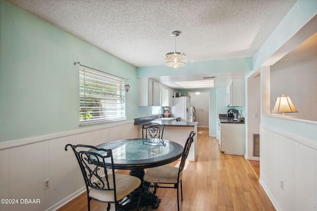 dining space with sink, a textured ceiling, and light hardwood / wood-style flooring