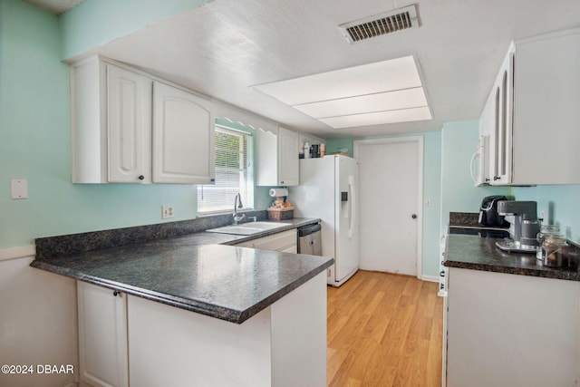 kitchen with sink, kitchen peninsula, white appliances, white cabinets, and light wood-type flooring