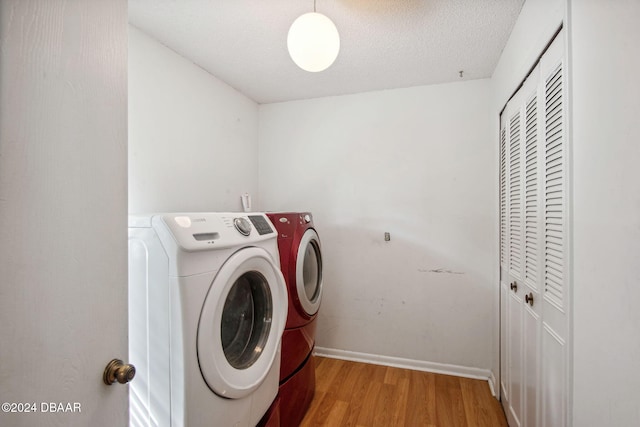 laundry room with a textured ceiling, light wood-type flooring, and washer and clothes dryer