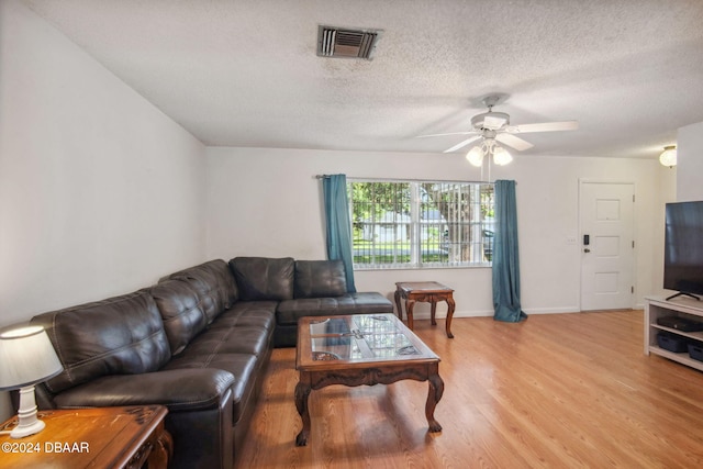 living room with light hardwood / wood-style floors, ceiling fan, and a textured ceiling