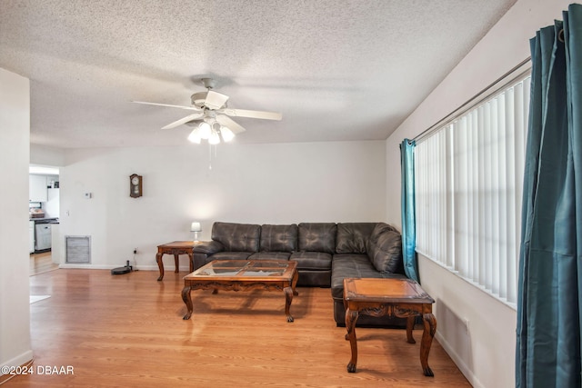 living room featuring light hardwood / wood-style flooring, a textured ceiling, and ceiling fan