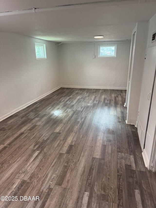 below grade area with visible vents, baseboards, and dark wood-style flooring