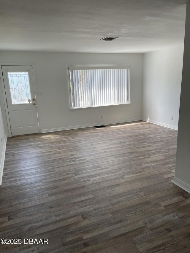 interior space featuring baseboards, dark wood finished floors, visible vents, and a healthy amount of sunlight