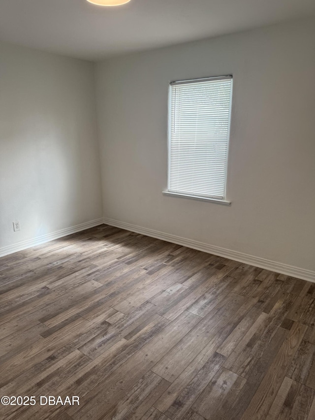 spare room with dark wood-type flooring and baseboards