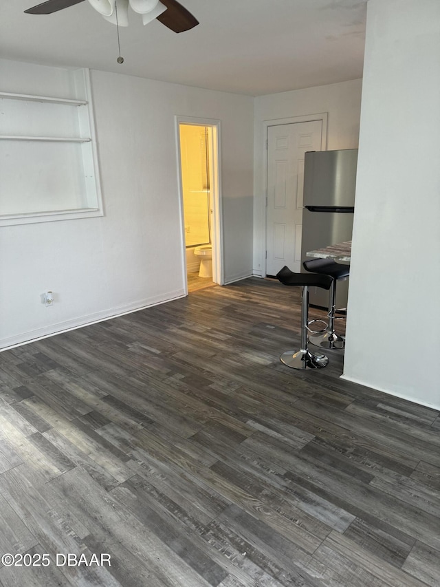 unfurnished room with baseboards, a ceiling fan, and dark wood-style flooring