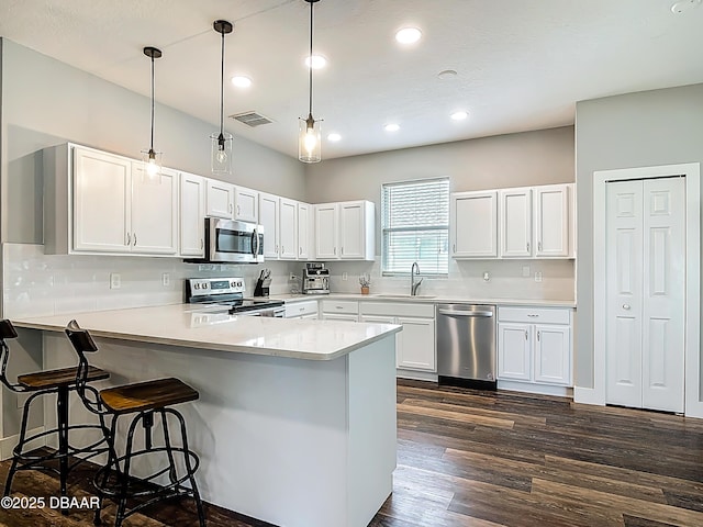 4225 Bristle Cone Way, Port Orange, FL 32129 - kitchen with appliances with stainless steel finishes, a peninsula, a breakfast bar, white cabinetry, and recessed lighting