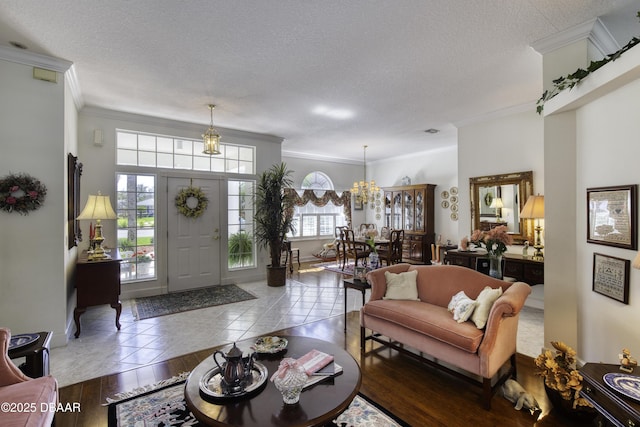 living area with wood finished floors, baseboards, a textured ceiling, crown molding, and a chandelier