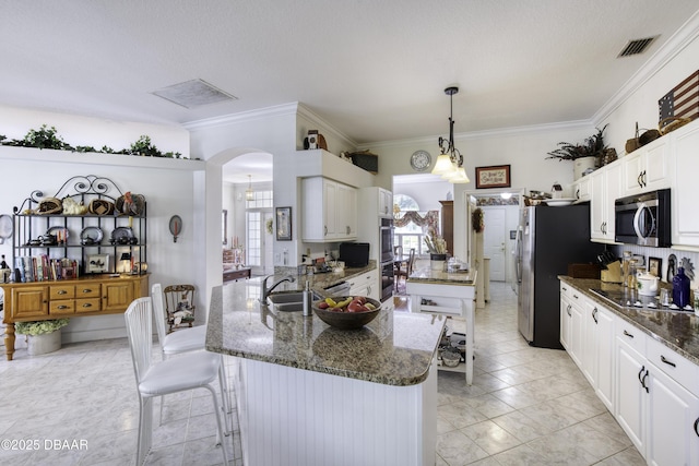 kitchen featuring dark stone countertops, visible vents, arched walkways, and appliances with stainless steel finishes