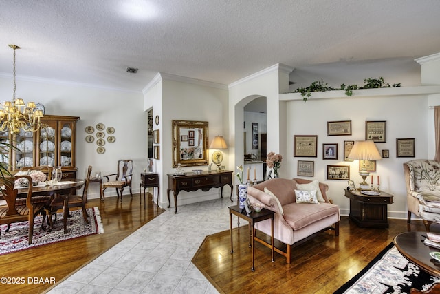 living area with arched walkways, a notable chandelier, and ornamental molding