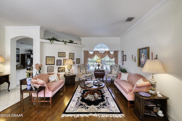 living room with visible vents, baseboards, ornamental molding, wood finished floors, and arched walkways