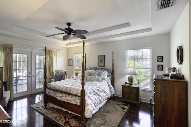 bedroom with visible vents, a raised ceiling, dark wood-type flooring, and access to exterior