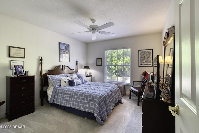 bedroom with a ceiling fan, light colored carpet, and a textured ceiling