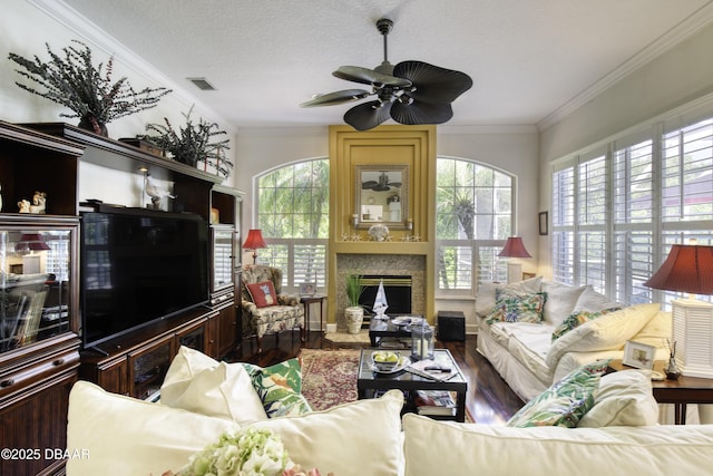 living room with plenty of natural light, wood finished floors, visible vents, and ornamental molding